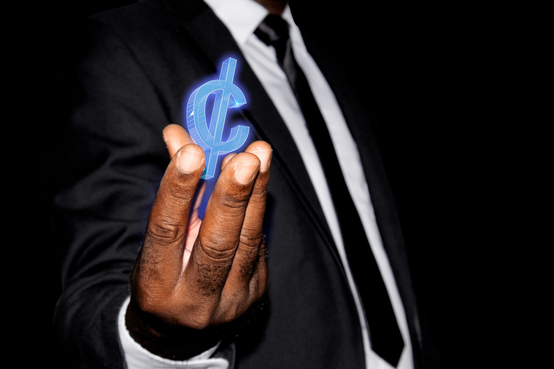 Black African businessman in suit and tie hand with blue 3D Ghanaian cedi hologram sign symbol floating hovering in on hand fingers over black dark background